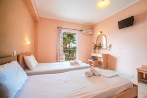 a bedroom with two beds and a window at APHRODITE APARTMENTS in Laganas
