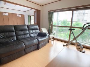 a living room with a leather couch and a treadmill at Itsukaichi First Villa Hiroshima in Hiroshima