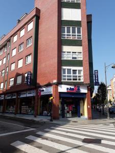 un edificio alto de ladrillo en una calle de la ciudad con un paso de peatones en Hotel Valdés, en Gijón