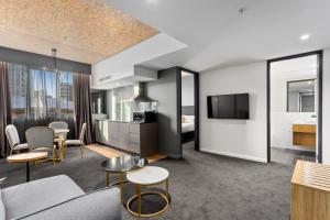 a living room with a couch and chairs and a tv at Hobart City Apartments in Hobart