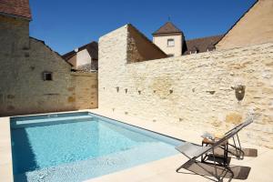a swimming pool in front of a stone wall with a chair at Le Charles V in Meursault