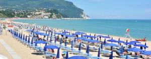 uma praia com muitos guarda-sóis azuis e o oceano em B&B La Casa di Isabella Loreto em Loreto