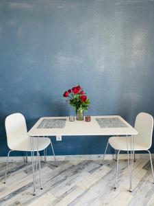 einen Tisch mit zwei Stühlen und eine Vase aus Blumen in der Unterkunft Сучасна 1-кімнатна квартира in Winnyzja