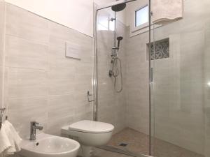 a bathroom with a shower and a toilet and a sink at Angolo Mare Apartments & Rooms in Porto Pino