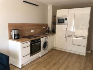 a kitchen with white cabinets and a sink and a refrigerator at Beg-Meil 200 m plage et sentiers T2 avec terrasse in Fouesnant