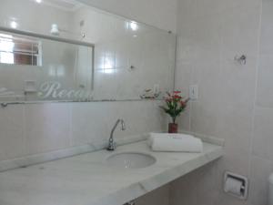 a white bathroom with a sink and a mirror at Pousada Recanto do Teimoso in Ubatuba