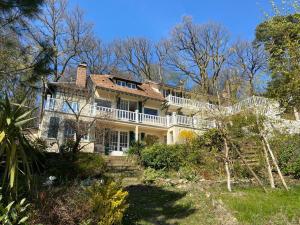 uma grande casa branca numa colina com árvores em Greeter-Maison campagnarde avec vue sur vallée à 30 min de la tour Eiffel em Jouy-en-Josas