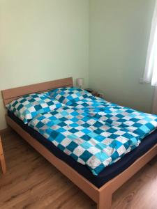 un letto con una coperta a scacchi blu e bianca. di Ferienwohnung Winkler a Rothenburg ob der Tauber