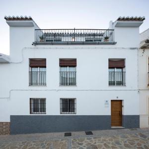 un edificio blanco con ventanas y puerta de madera en ATICO CASAENMEDIO, en Valle de Abdalajís