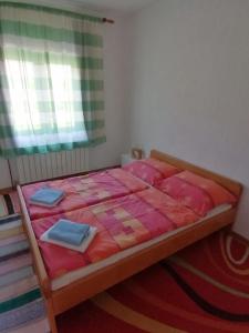 Schlafzimmer mit einem Bett mit rosa Bettwäsche und einem Fenster in der Unterkunft Apartman Juka in Krasno Polje