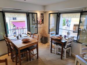 a dining room with two tables and chairs and windows at La Victoire Boutique Hotel in Vence