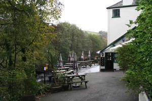 a group of picnic tables with umbrellas and a building at The Abbey Inn in Buckfastleigh