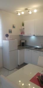 kuchnia z białymi szafkami i białą lodówką w obiekcie Apartment Rosana w Rabacu