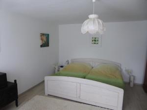 Schmidts Naturhof في Laaslich: سرير أبيض في غرفة بيضاء مع ثريا