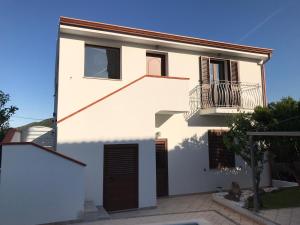 a white house with a balcony and a staircase at B&B Aly&Emy in Limpiddu