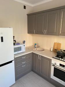 a kitchen with a white refrigerator and a sink at 2-ухкомнатная современная новая квартира в центре города in Kostanay