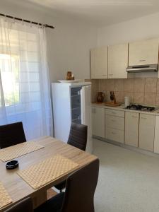 a kitchen with a table and a white refrigerator at Apartmans and rooms ''Slavica'' in Novalja