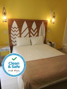 a bedroom with a bed with a clean and safe sign on it at By the Beach in Nazaré