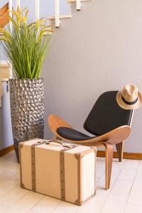 uma cadeira e uma mala ao lado de uma cadeira e uma cadeira com um chapéu em Hotel Veleiro em Sines