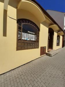 un edificio amarillo con una ventana con un cartel. en Penzion Fontána, en Mikulov