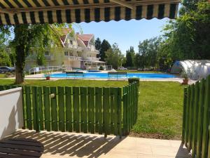 a green fence in front of a yard with a pool at Mira Apartman in Keszthely