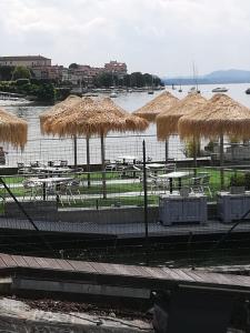 a restaurant with tables and straw umbrellas and a body of water at Residenza Silvana Apt Cielo and Apt Giardino on the ground floor with parking in Verbania