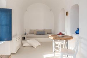 a white room with a table and a bed at White Cellar cave houses by Cycladica in Oia