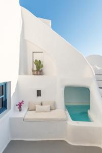 a white house with a swimming pool under the stairs at White Cellar cave houses by Cycladica in Oia