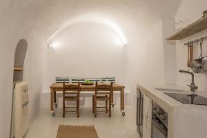 a kitchen with a wooden table and chairs at White Cellar cave houses by Cycladica in Oia