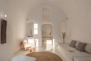 a white living room with a couch and a chair at White Cellar cave houses by Cycladica in Oia