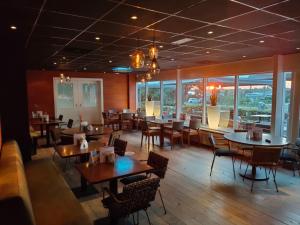 a dining room with tables and chairs and windows at 't VeerHuys in Beusichem