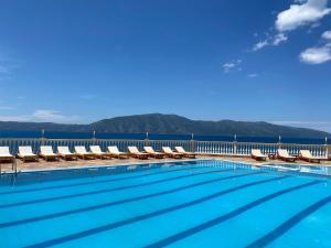 a swimming pool with chairs and mountains in the background at Hakunna Matata Residence & Apartments in Vlorë