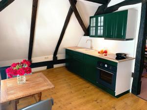una cocina con armarios verdes y una mesa con flores en Historische Ferienwohnung mit Kamin in Lich, en Lich