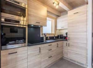 a kitchen with wooden cabinets and stainless steel appliances at Les Ours de Combloux in Combloux