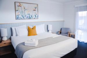 ein Schlafzimmer mit einem großen weißen Bett mit gelben Kissen in der Unterkunft Eight Spence in Warrnambool