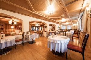 ラ・ヴィッラにあるHotel Dolomitiの白いテーブルクロスのテーブル2台付きレストラン