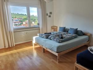 Bett in einem Zimmer mit einem großen Fenster in der Unterkunft Ferienwohnung "Burgpanorama" in der Südpfalz in Leinsweiler