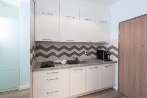 a kitchen with white cabinets and a sink at Studio w parku nad zatoką in Puck