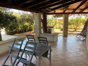 patio con tavolo e sedie sotto il portico di Appartamenti in villa Senia a Favignana