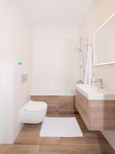 a white bathroom with a toilet and a sink at Studio w parku nad zatoką in Puck