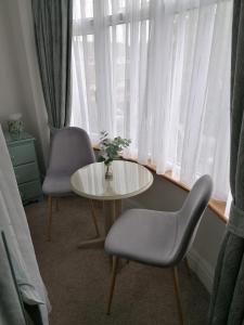 ペイントンにあるBlue Waters Lodgeのテーブルと椅子2脚、窓が備わる客室です。
