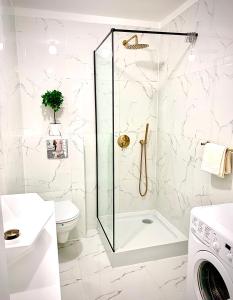 een witte badkamer met een douche en een toilet bij Apartament Bursztynek Jantar Park in Jantar