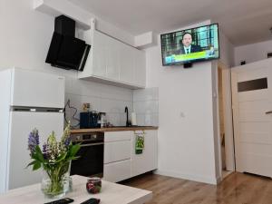 uma cozinha com armários brancos e uma televisão na parede em Apartament De Luxe Emily em Jelenia Góra