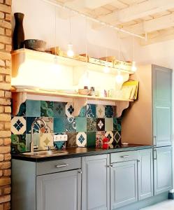 a kitchen with white cabinets and tiles on the wall at Villa Arany in Balatonszemes