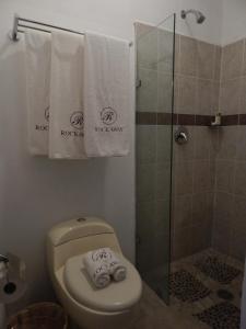 a bathroom with a toilet and a shower with towels at Hotel Rockaway in Puerto Escondido