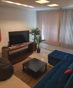 sala de estar con sofá azul y TV de pantalla plana en Apartamento Barão da Torre, en Río de Janeiro