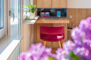 a red chair sitting next to a desk with a laptop at 9th floor Skwer Kościuszki z widokiem na morze in Gdynia