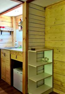 a kitchen with wooden walls and a counter with shelves at Chatka Gargamela in Mikołajki +15 photos