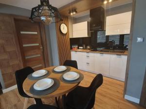 a dining room table with chairs and a clock in a kitchen at BALTIC PLAŻA przy plaży in Krynica Morska