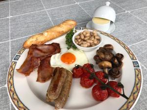 a plate of breakfast food with eggs bacon mushrooms and tomatoes at Beacon House B&B Brixham in Brixham